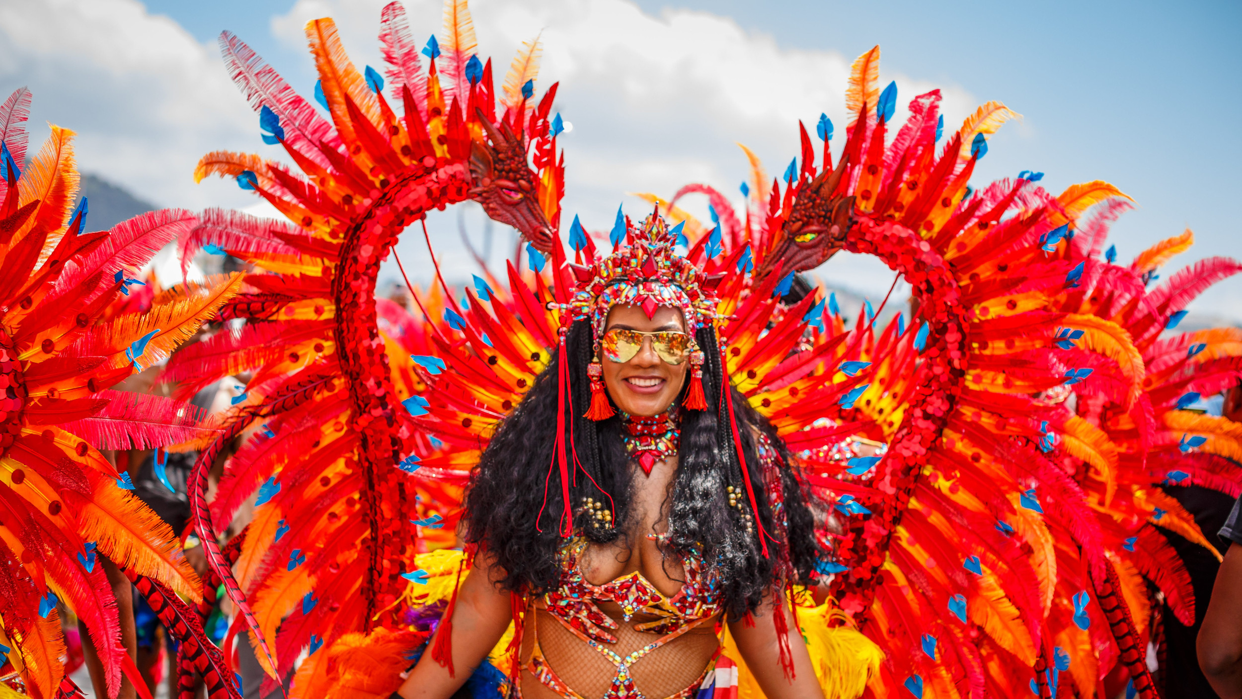 Masqueraders moving through crowded streets in Port of Spain during Trinidad Carnival, surrounded by music, motion, and heat